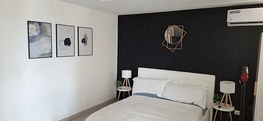 Bedroom with dark feature wall, new flooring and framed art hung level.